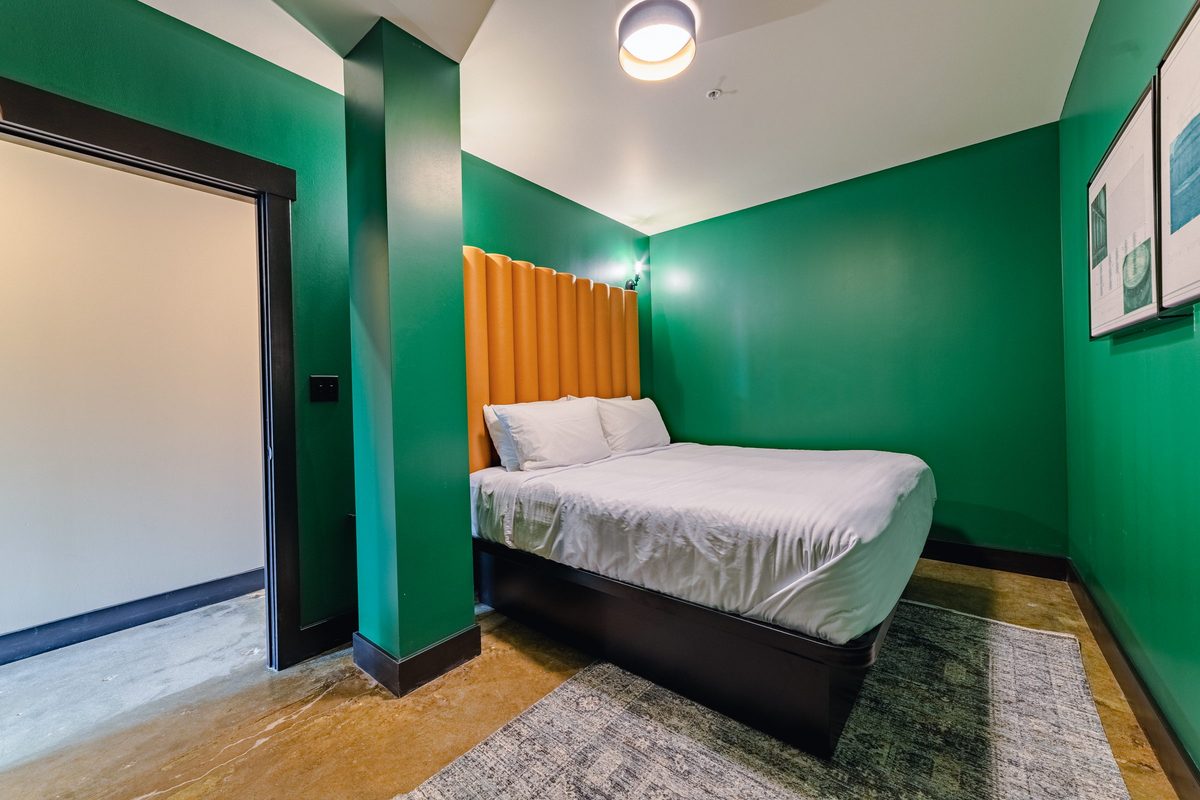 King bedroom with green walls and channel-tufted headboard